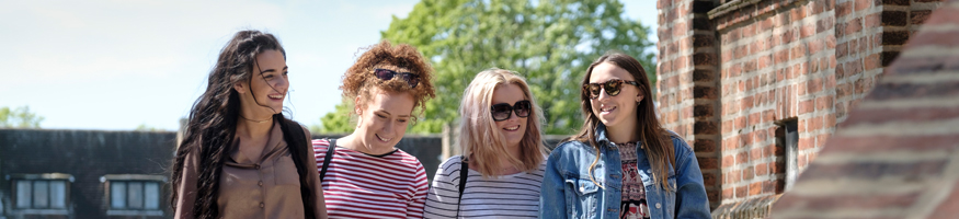 Four students walking along pathway talking